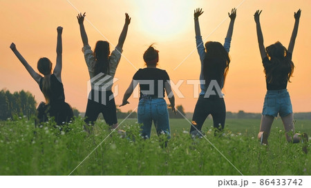 Girls friends are jumping against the background of an evening summer sunset. Girls friends are jumping against the background of an evening summer sunset. 86433742