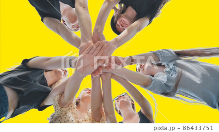 Cheerful female friends join hands on a yellow background as a sign of strong friendship. 86433751