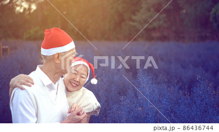 Lovely happy Asian elder couple Christmas celebration with red santa claus hat in magic purple flower field morning 86436744