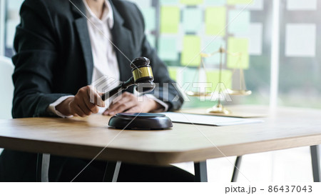 Young woman lawyer holding wooden gavel with blurry golden scales. 86437043