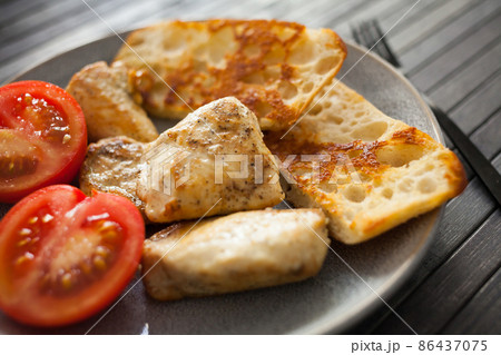toasted pieces of chicken breast, toast and tomatoes on plate 86437075