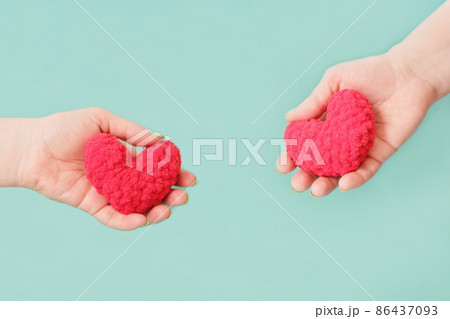 female hands holding knitted red hearts on turquoise background. love and valentines day concept. relationship and family, dating and engagement. 86437093