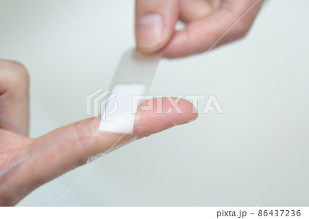 絆創膏を貼る女性の指 86437236