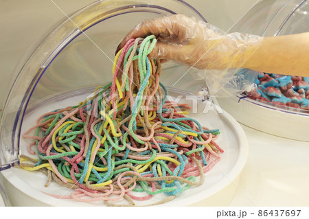 a girl in a disposable glove types chewing marmalade strips of worms.Close-up, the use of disposable gloves protective equipment compliance with sanitary standards 86437697