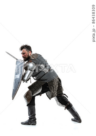 Portrait of brave medieval warrior, knight in special armor protecting himself with shield and sword isolated over white studio backgrond 86438309