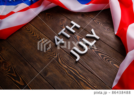 the words 4th july and crumpled usa flag on flat textured wooden surface background 86438488