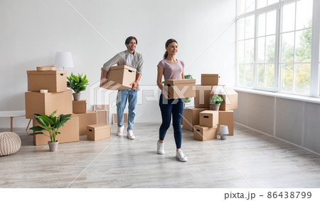Satisfied happy millennial caucasian male and female carry cardboard boxes, enjoy moving in empty apartment 86438799