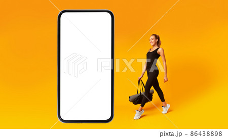 Fitness Woman Walking To Big Smartphone Blank Screen, Yellow Background Fitness Woman Walking To Big Smartphone Blank Screen, Yellow Background 86438898