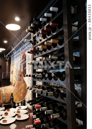 Bottles of wine stacked in cellar room, jamon iberico, Spanish style Bottles of wine stacked in cellar room, jamon iberico, Spanish style 86439833