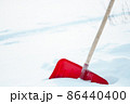 Close up of big red plastic showel in the process of removing snow in winter 86440400