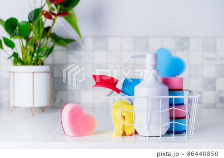 Housekeeping concept. Washing soap, heart shaped sponges, brush and napkins in the basket on the table with green plant. Selective focus. Copy space. Housekeeping concept. Washing soap, heart shaped sponges, brush and napkins in the basket on the table with green plant. Selective focus. Copy space. 86440850