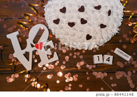 white cream cake or meringue cake for valentine's day. The world love in wooden letters. The calendar is February 14. on a natural wooden background. 86441148
