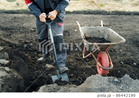 Working with garden tools, shovel and wheelbarrow on the site of a country house. Preparation for construction work. Working with garden tools, shovel and wheelbarrow on the site of a country house. Preparation for construction work. 86442190