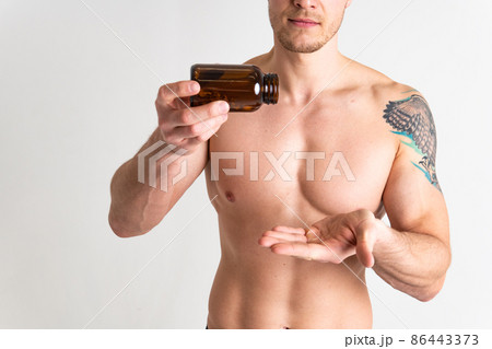 Fish oil is eaten by a man in the hands of vials and a glass bottle capsule vitamin, medicine tablet liver 3, gel cod. white fat, care female giving dieting 86443373