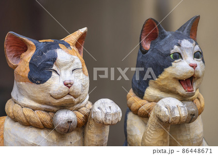 [東京・谷中] 谷中銀座商店街の前脚を挙げる阿形吽形姿の木造彫刻の招き猫。 86448671