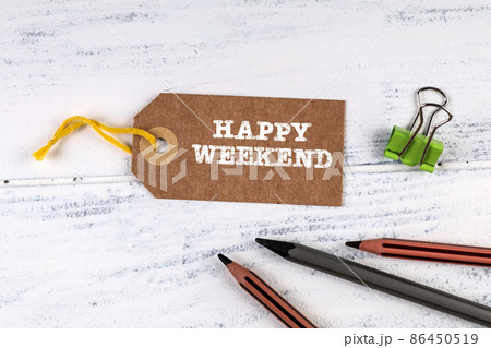 Happy Weekend. Cardboard price tag and pencils on a white wooden background Happy Weekend. Cardboard price tag and pencils on a white wooden background 86450519