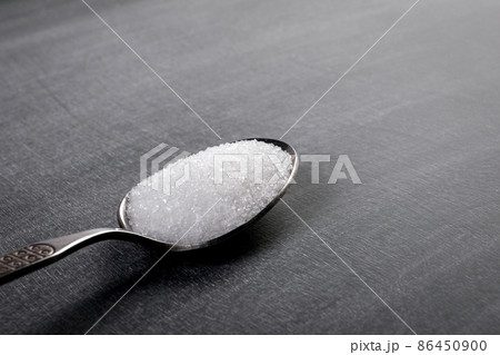 Teaspoon with white sugar on a chalk board background 86450900