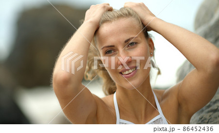 Beautiful woman poses for the camera on a beach at the ocean 86452436