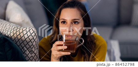 Young pretty woman drinks a cup of tea while lying on the couch 86452798
