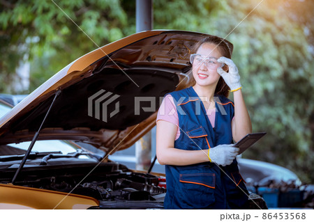 Woman car mechanic wearing glass and glove open car hood repairing check car problem system check detail for maintenance and fixed in car garage. Woman car mechanic wearing glass and glove open car hood repairing check car problem system check detail for maintenance and fixed in car garage. 86453568