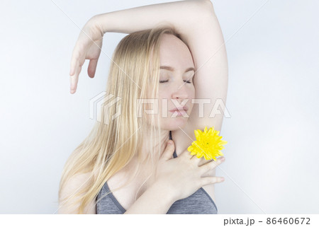 Concept of a pleasant smell from the armpits. Girl has yellow flowers sandwiched between her arms and chest. Body care. Women Health. Chrysanthemums. Bodypositive and struggle for female naturalness 86460672