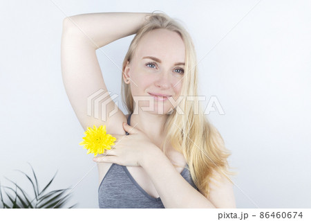 Concept of a pleasant smell from the armpits. Girl has yellow flowers sandwiched between her arms and chest. Body care. Women Health. Chrysanthemums. Bodypositive and struggle for female naturalness Concept of a pleasant smell from the armpits. Girl has yellow flowers sandwiched between her arms and chest. Body care. Women Health. Chrysanthemums. Bodypositive and struggle for female naturalness 86460674