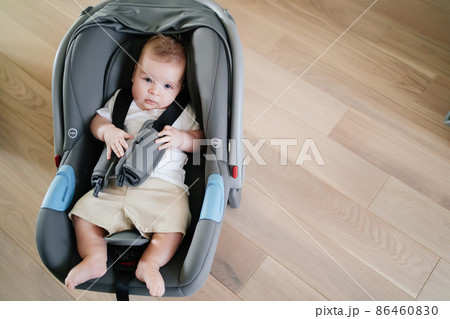 a little boy lies strapped in a stroller-carrier. a little boy lies strapped in a stroller-carrier. 86460830