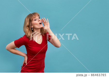 Young woman put her hand to face and shout to someone isolated on blue background. Copy, empty space for text Young woman put her hand to face and shout to someone isolated on blue background. Copy, empty space for text 86463765