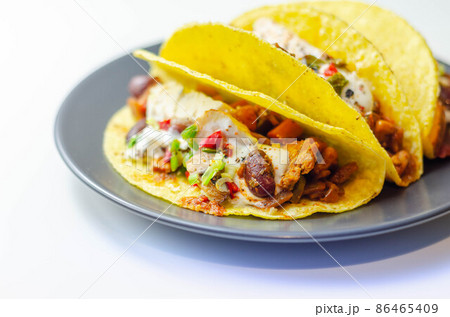 Mexican tacos shells with chicken and red kidney beans, onion,  red and green peppers, and salsa sauce 86465409