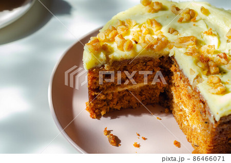 Sliced carrot cake filled and topped with cream cheese buttercream and decorated with walnuts 86466071