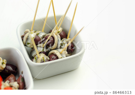 The traditional Spanish appetizers of olives, tomatoes and anchovies in a white ceramic bowls The traditional Spanish appetizers of olives, tomatoes and anchovies in a white ceramic bowls 86466313