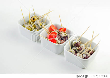 The traditional Spanish appetizers of olives, tomatoes and anchovies in a white ceramic bowls The traditional Spanish appetizers of olives, tomatoes and anchovies in a white ceramic bowls 86466314
