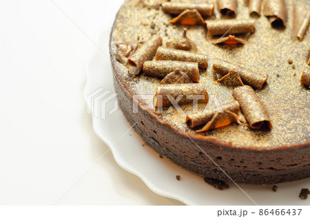 Digestive biscuit base with chocolate cheesecake and pockets of salted caramel sauce, topped with chocolate ganache, milk chocolate curls, and gold shimmer 86466437