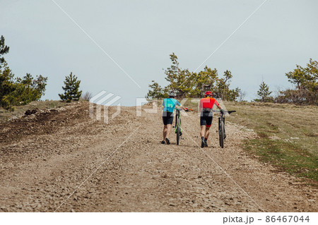 two cyclists go uphill with their mountain bikes 86467044
