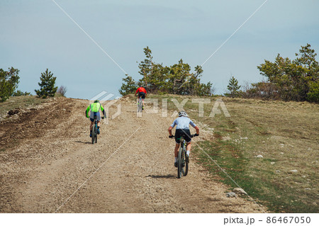 three athletes cyclists riding uphill on mountain bike 86467050