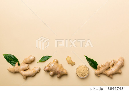 Finely dry Ginger powder in bowl with green leaves isolated on colored background. top view flat lay Finely dry Ginger powder in bowl with green leaves isolated on colored background. top view flat lay 86467484