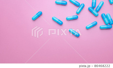 Top view capsule pills on pink background. Prescription drugs. Blue capsule pills. Pharmaceutical industry. Medicament and pharmacology. Drug development and new drug research. Capsule pills industry. 86468222