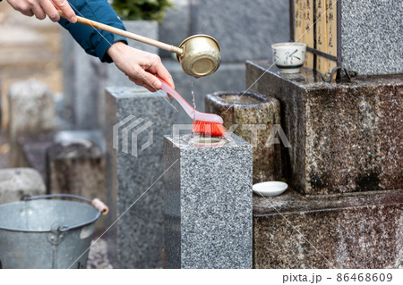 お墓参りに来てお墓の掃除をしている男性 86468609