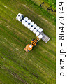Tractor loading winter feed for livestock on a trailer 86470349