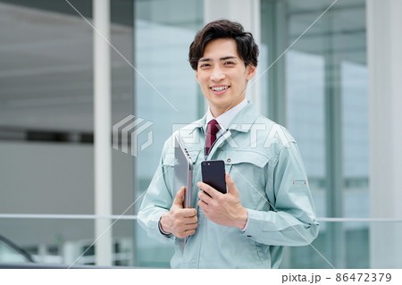 オフィスで働くスマホを操作する作業服のエンジニア オフィスで働くスマホを操作する作業服のエンジニア 86472379
