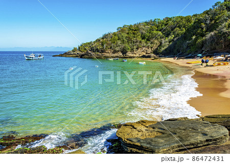 Paradise beach with colorful transparent waters surrounded by stones and vegetation Paradise beach with colorful transparent waters surrounded by stones and vegetation 86472431