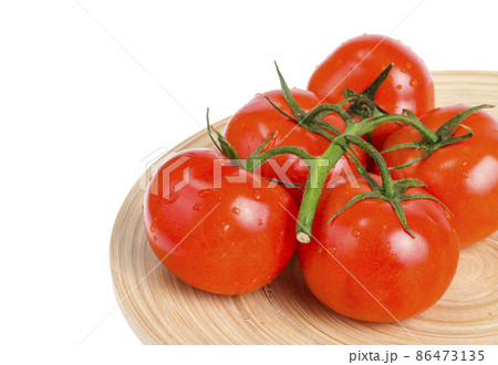 Branch of ripe red tomatoes on wooden dish. 86473135