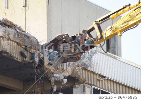 老朽化した公共建造物の解体作業をする重機 86476935