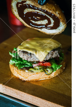 Rich cheeseburger in making, fluffy buns, beef burger meat, lettuce, bbq sauce and cheese. Rich cheeseburger in making, fluffy buns, beef burger meat, lettuce, bbq sauce and cheese. 86477625