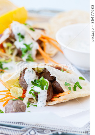 Homemade lamb meatballs in pita flatbread with spicy yoghurt sauce. Close up. Homemade lamb meatballs in pita flatbread with spicy yoghurt sauce. Close up. 86477638
