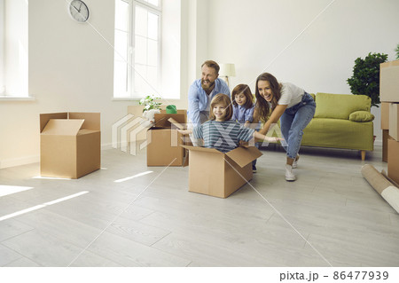 Happy family with children having fun in new home. Excited first-time buyers laughing and playing with boxes in spacious living room interior. Real estate, residential mortgage, buying house concept Happy family with children having fun in new home. Excited first-time buyers laughing and playing with boxes in spacious living room interior. Real estate, residential mortgage, buying house concept 86477939