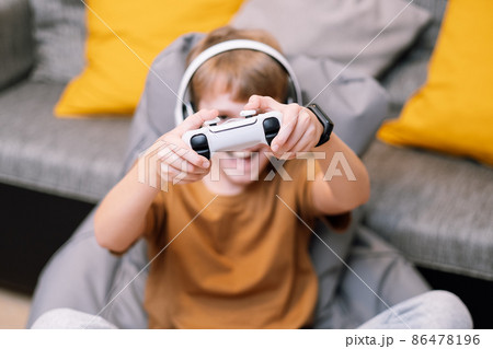 Teen boy with headphones and joystick playing video game console. 86478196