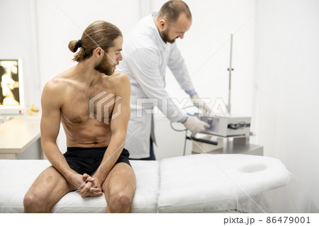 Senior doctor prepares device for shock-wave therapy 86479001