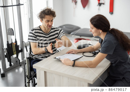 Rehabilitation specialist consulting man in wheelchair before training Rehabilitation specialist consulting man in wheelchair before training 86479017