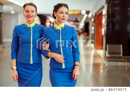 Female flight attendants standing arm in arm at airport Female flight attendants standing arm in arm at airport 86479075